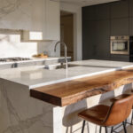 A modern kitchen island with seating featuring a combination of cold marble surfaces and warm walnut wood to influence social flow.