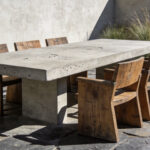 A minimalist patio design featuring a raw concrete table and weathered wood seating to showcase the philosophy of materiality and texture.